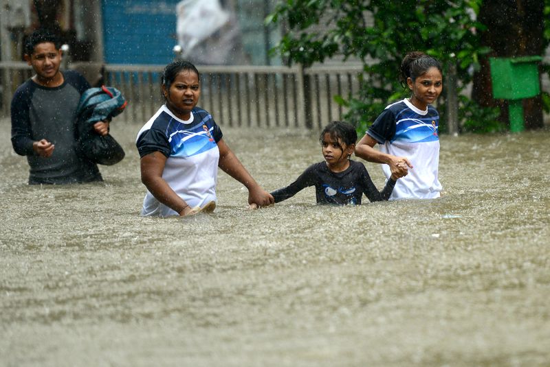 Indians wade through a flooded street during heavy rain showers in Mumbai on August 29, 2017. (Image Source: theguardian.com)