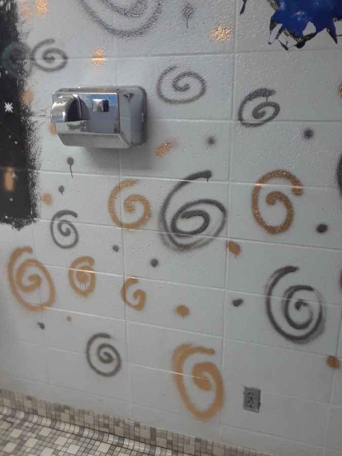 Spray paint swirls on the wall next to the sinks.