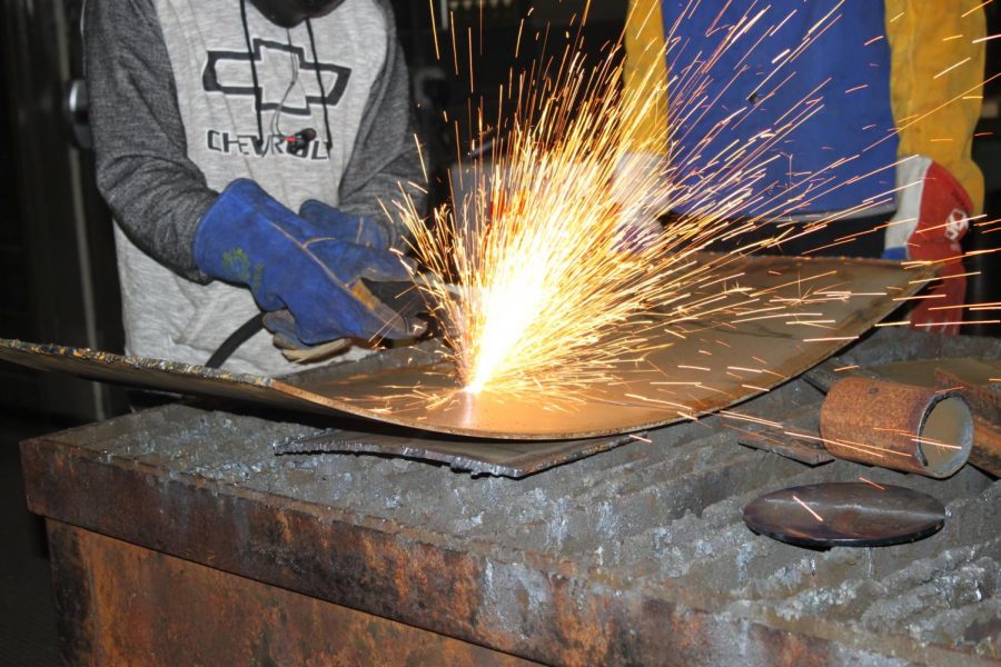 Donald Dunn (10) cuts a piece of metal before he welds it. 