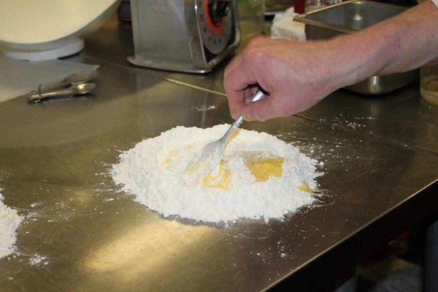 Chef teaches the class how to beat an egg into flour. 