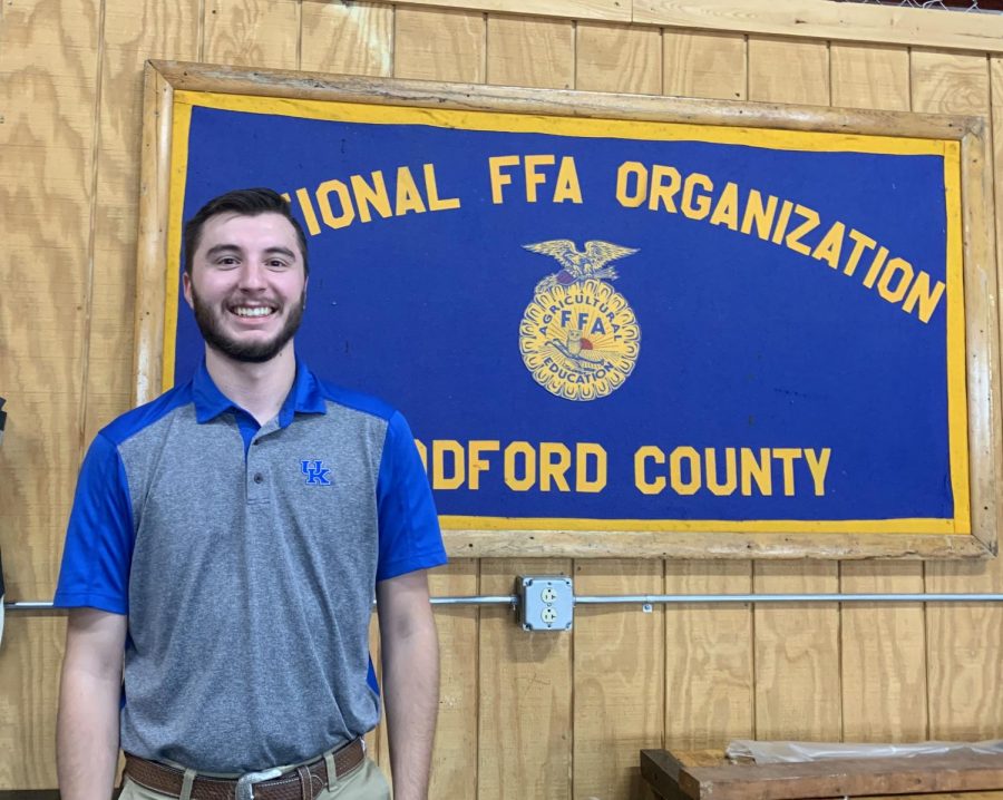 Mr. Bedard poses with the FFA poster located in the workshop room.

