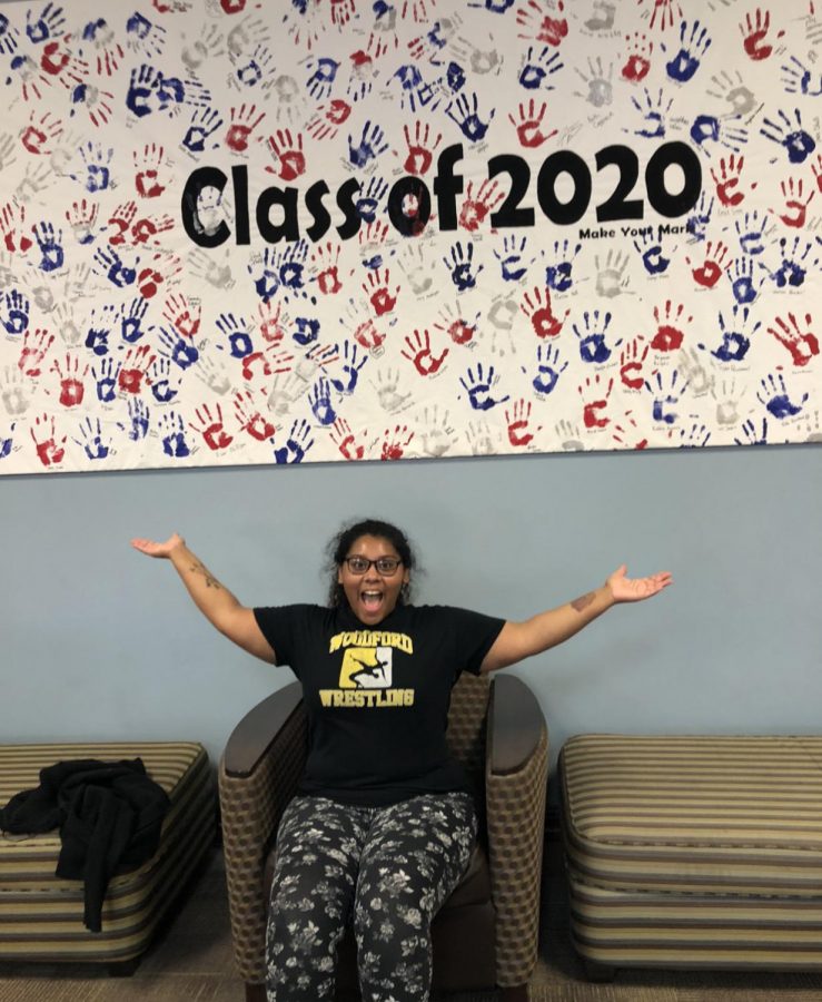 Senior (12) MaQuoia Bernabe posing in front of a ¨Class of 2020¨ artwork. 