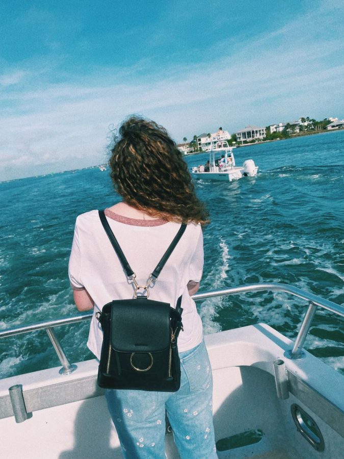 Katelyn stands on the back deck of the ship and looks out at the sea. 