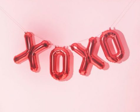 A very fun and bright Valentines Day balloon display taken in front of a soft pink background.