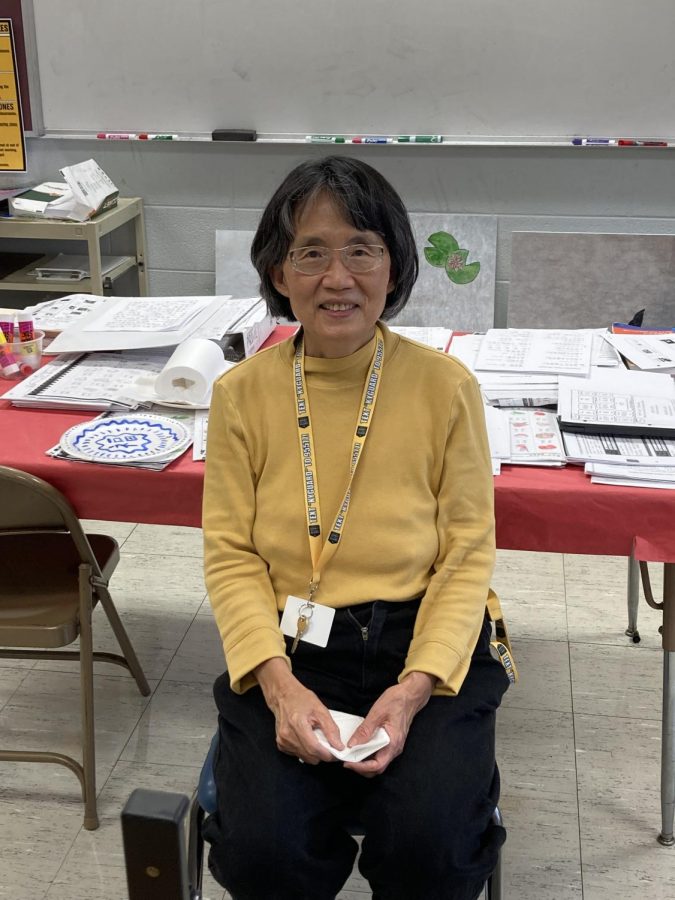 Ms. Chou sits at her desk in her classroom.