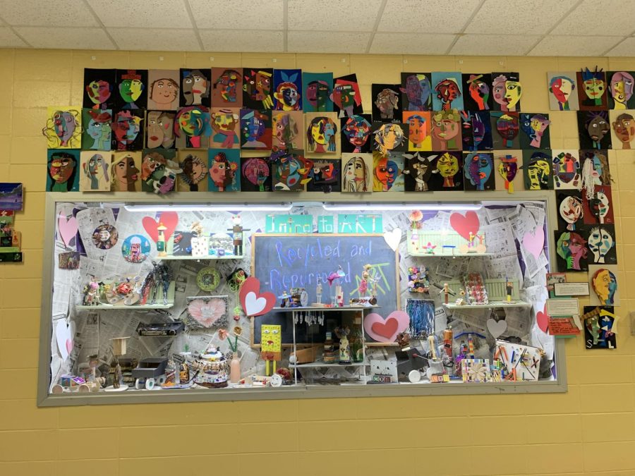 Front office display titled Recycled and Repurposed. All around is 3-D Picasso Portraits done by students.  