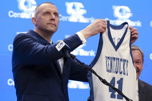 Mark Pope, holding up his jersey from when he played at the University of Kentucky. 