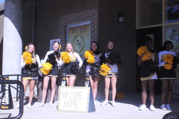 WCHS Cheer Squad welcoming in people in front of the school. 