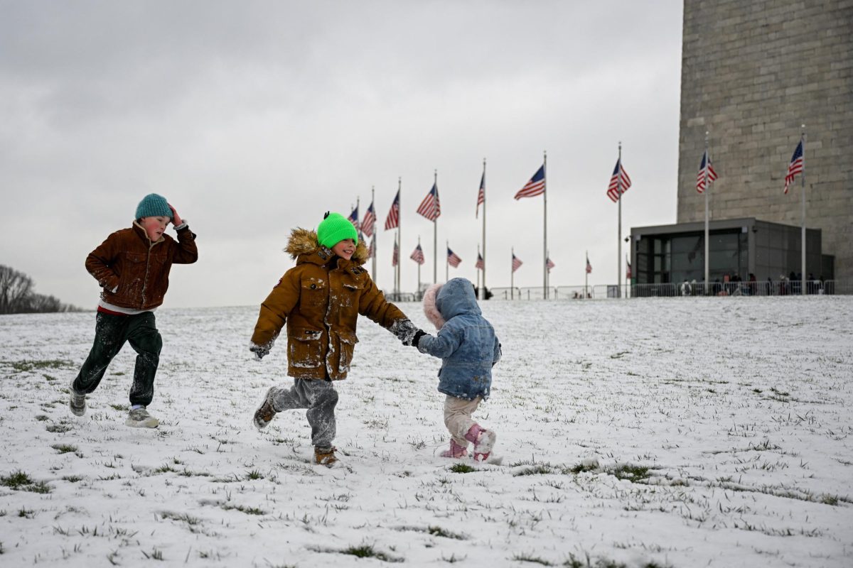 Gabriel Tritt, 9, Mads Lichtwerch, 6, and Saga Lichtwerch, 2, run in the snow near the Washington Monument after the first snow of the winter season, in Washington, D.C., U.S., December 5, 2025. REUTERS/Daniel Heuer